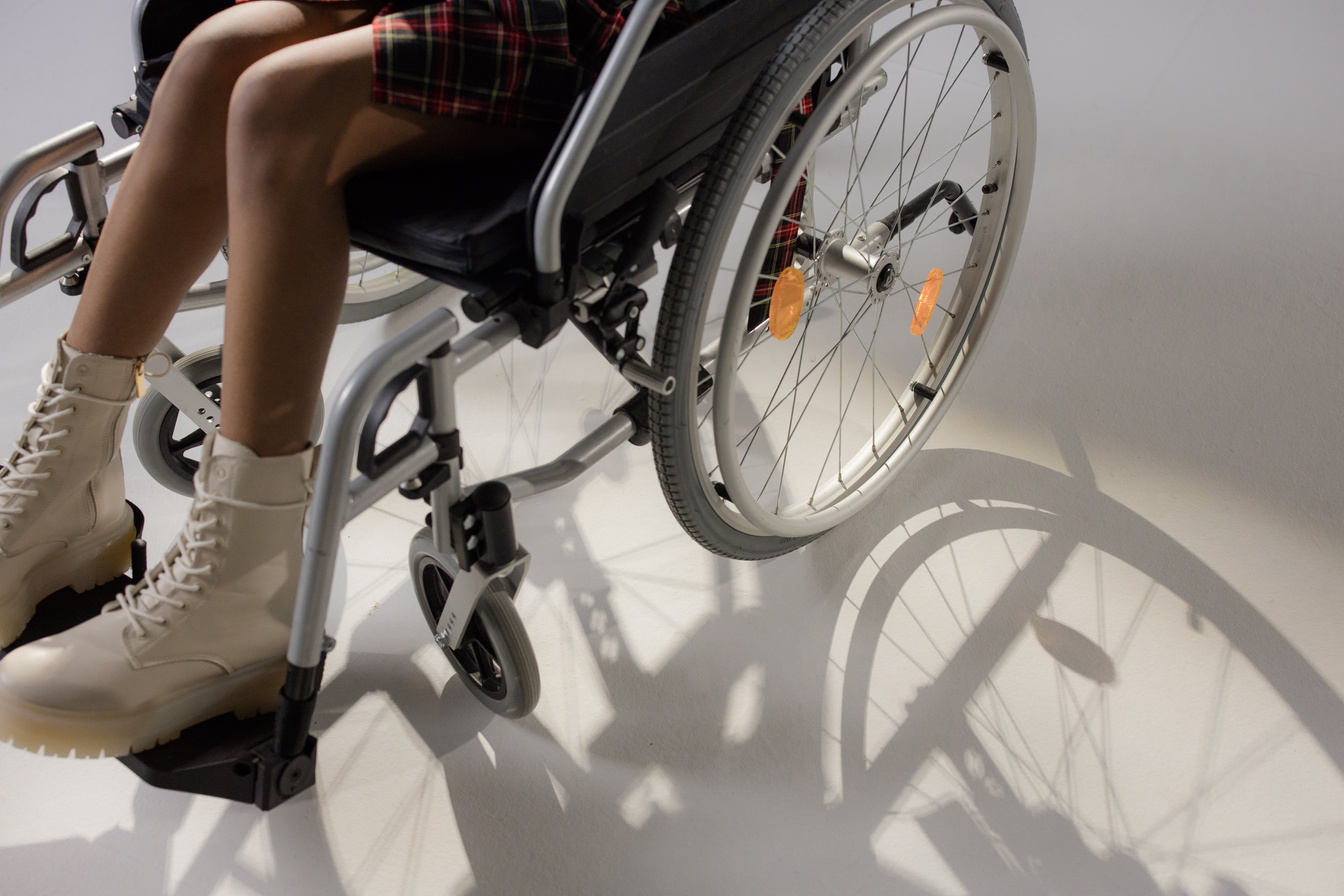 Young Girl in Plaid Skirt Sitting on Black Wheelchair